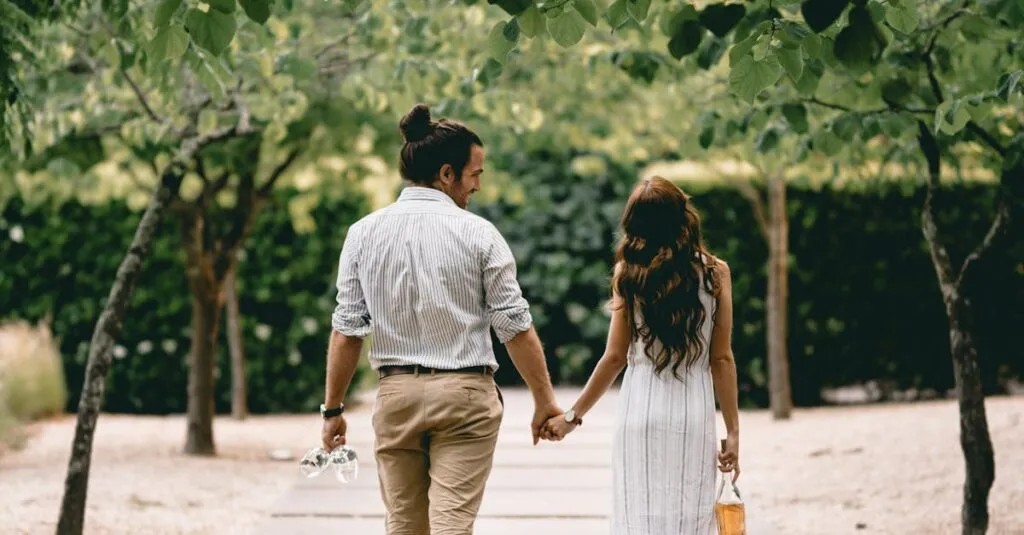 Couple walking hand-in-hand down a tree-lined path, embracing nature and romance.